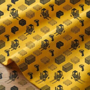 May include: Yellow fabric with a repeating pattern of black line art illustrations. The design includes forklifts, shipping containers, pallets, boxes, and barcode scanners. The fabric is folded, creating shadows and texture.