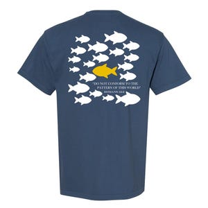 May include: Navy blue t-shirt featuring a design of white fish swimming in one direction, with a single yellow fish swimming in the opposite direction. The text "DO NOT CONFORM TO THE PATTERN OF THIS WORLD" and "ROMANS 12:2" is printed below the fish.