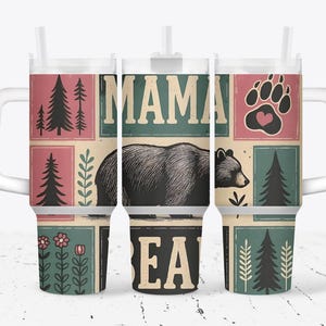 Puede incluir: Un termo blanco con asa, con un diseño con las palabras "MAMA BEAR" y una ilustración de oso. El diseño incluye árboles, flores y una huella de pata con un corazón.