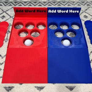Peut inclure: Jeux de société rouge et bleu avec six trous chacun, une balle de golf dans chacun et le texte "Add Word Here" sur chaque planche. Comprend des pièces de jeu circulaires rouges et bleues. Un jeu amusant pour tous les âges.