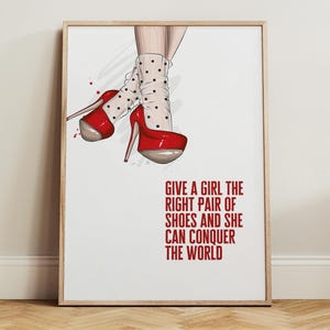May include: A framed print featuring a fashion illustration of red high-heeled shoes with a platform sole. The illustration includes white socks with black polka dots. The text reads: "GIVE A GIRL THE RIGHT PAIR OF SHOES AND SHE CAN CONQUER THE WORLD."