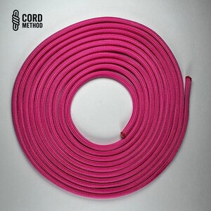 Op de afbeelding: Opgerold helderroze touw. Het touw is in een cirkelvormig patroon gewikkeld, met het uiteinde van het touw naar buiten uitstekend. De tekst "CORD METHOD" staat linksboven in het zwart.