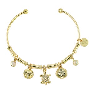 May include: Gold-toned bangle bracelet featuring sea-themed charms. The bracelet includes a seashell, a turtle, and a sand dollar charm, all adorned with sparkling accents. The bracelet also has a small round charm with the text "VIVA LIFE".