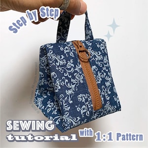 May include: A small blue fabric pouch with a white floral pattern, featuring a brown vertical zipper closure and a top handle. The text "Step by Step", "SEWING tutorial with 1:1 Pattern", and "© 2026 Dickeltso. All rights reserved" is visible.