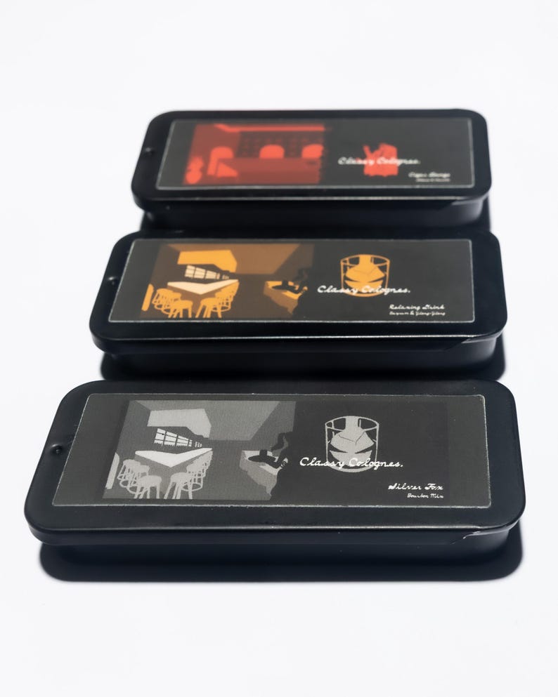 May include: Three black rectangular tins with transparent lids are stacked. Each tin features a different graphic illustration and the text "Classy Colognes." The top tin has a red bar scene, the middle tin has a brown bar scene, and the bottom tin has a gray bar scene.