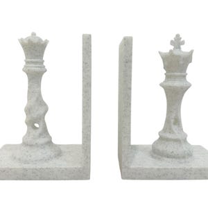 May include: Chess-themed bookends in a speckled white finish. The set includes two pieces, each featuring a chess piece design: a queen and a king. The bookends are designed to hold books upright and add a decorative touch to any bookshelf.