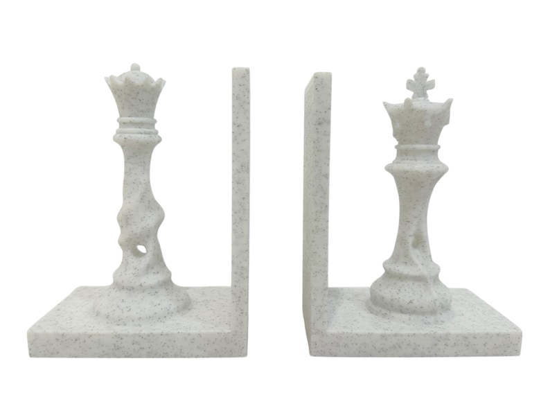 May include: Chess-themed bookends in a speckled white finish. The set includes two pieces, each featuring a chess piece design: a queen and a king. The bookends are designed to hold books upright and add a decorative touch to any bookshelf.