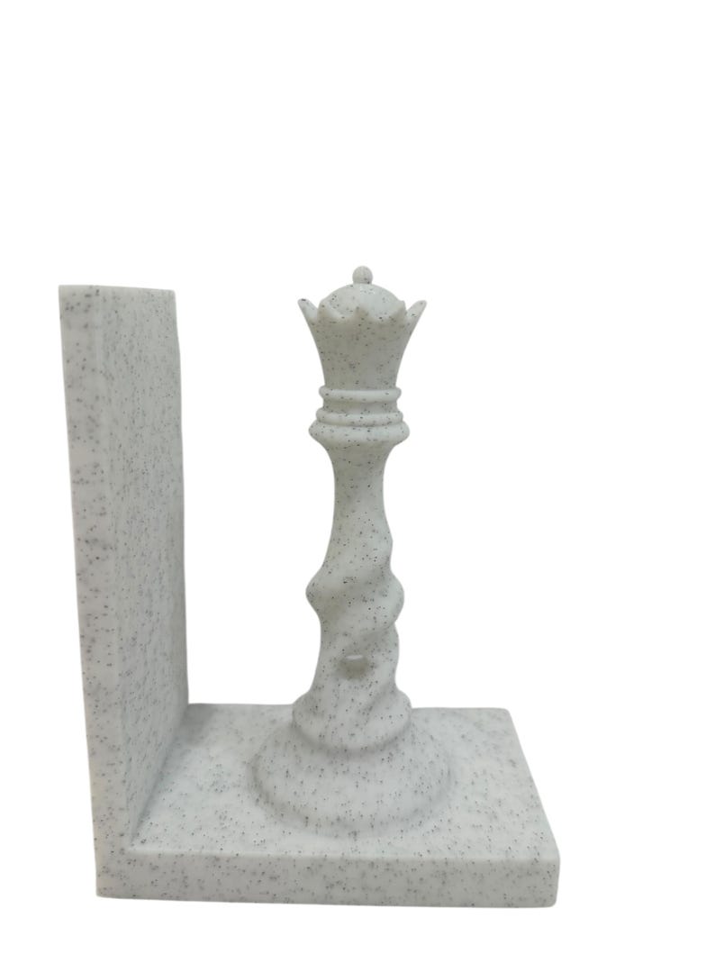 May include: A speckled white chess queen bookend. The queen piece is intricately detailed with a crown and a twisted stem. The bookend has a rectangular base and a vertical support, perfect for holding books.