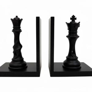 May include: Black chess piece bookends featuring a queen and a king. The bookends are made of a dark, textured material and are designed to hold books upright. The chess pieces are detailed and add a touch of elegance to any bookshelf.