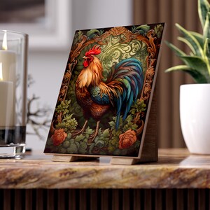 Può includere: Un cartello da tavolo rettangolare con una vivace illustrazione di un gallo con piume arancioni, rosse e blu. Il gallo è incorniciato da volute marroni decorate e circondato da fogliame verde e fiori di rosa arancioni.