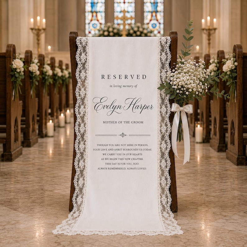 May include: A white fabric memorial sign draped over a wooden chair, featuring black text that reads RESERVED in loving memory of Evelyn Harper MOTHER OF THE GROOM, bordered by intricate white lace trim and adorned with a bouquet of baby's breath.
