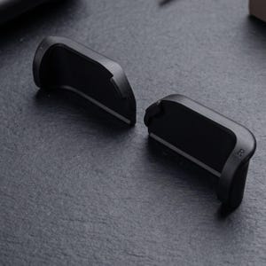 May include: Two matte black plastic controller trigger attachments with curved edges. Each piece features a distinct letter embossed on the side, with one marked with an L for left and the other marked with an R for right, indicating their specific placement.