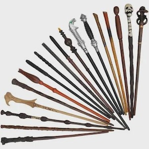 May include: A collection of fifteen distinct wands arranged in a fan shape. The wands feature various designs, including wooden textures, metallic accents, a skull topper, and intricate carvings in shades of brown, black, silver, and tan.