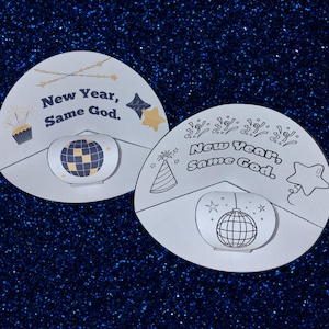 May include: Two white, semi-circular paper cutouts with the text "New Year, Same God." One has a disco ball graphic and a cupcake. The other has a disco ball graphic, a party hat, and a star. The background is a dark blue, glittery surface.