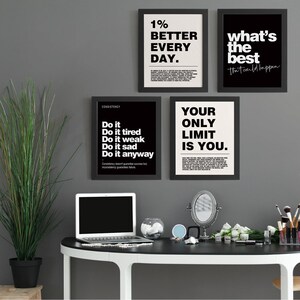 May include: Four framed motivational posters with black frames and white or black backgrounds. The posters display phrases like "1% Better Every Day" and "Your Only Limit Is You." A laptop and vanity mirror are on a black desk.