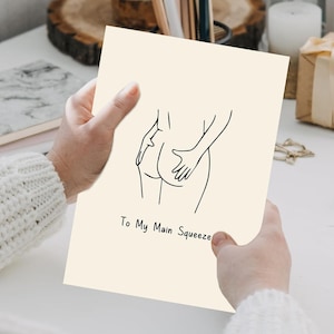 May include: A cream-coloured greeting card featuring a black line drawing of a person's backside being touched. The text "To My Main Squeeze" is printed in black below the illustration.