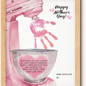 May include: A framed print with a pink watercolor illustration of a stand mixer, a handprint, and text. The text reads "Happy Mother's Day!" and "A spoonful of love...just like you!" The print is in a light wood frame.