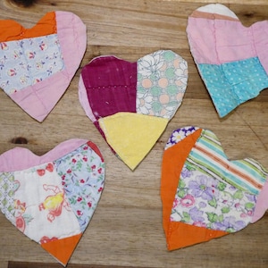 May include: Five patchwork heart-shaped fabric ornaments in various colors and patterns, including pink, blue, green, orange, and yellow.