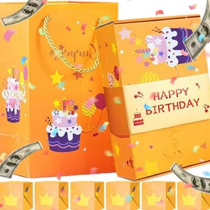 May include: Orange gift bag and box set with birthday cake illustrations, confetti, and the words "Happy Birthday." The bag has a gold rope handle. Small yellow boxes with crown designs are at the bottom.