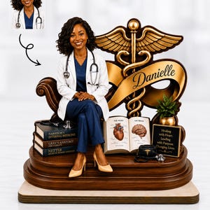 May include: A custom figurine of a doctor wearing a white coat and blue scrubs, seated on a base featuring a caduceus symbol with the name Danielle. The display includes miniature medical textbooks, an open anatomy book, and a plaque.