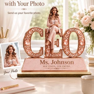 May include: A personalized desk ornament featuring the letters CEO in rose gold with embedded crystals. A miniature figure of a person in a rose gold suit sits on the letter E. The base displays the text Ms. Johnson and HER VISION, HER EMPIRE.