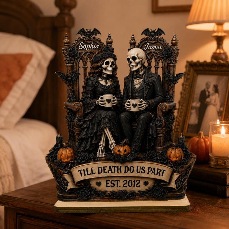 May include: A decorative figurine featuring two skeletons seated on ornate thrones, holding mugs with heart icons. The base displays the text "TILL DEATH DO US PART" and "EST. 2012" with pumpkins and roses. The names "Sophia" and "James" are engraved above.