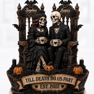 May include: A decorative figurine featuring two skeletons seated on ornate thrones, holding mugs with heart icons. The female skeleton wears a black dress and the male wears a black suit. A banner reads TILL DEATH DO US PART EST. 2012 with names Sophia and James.