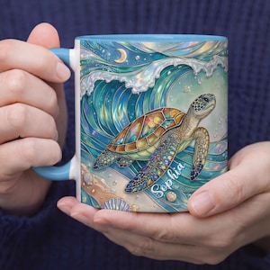 May include: A ceramic mug with a blue handle and rim, featuring a colorful illustration of a sea turtle swimming in front of a wave. The turtle has a patterned shell and the name "Sophia" is written on the mug.