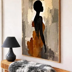 K&ouml;nnte beinhalten: Ein rechteckiges Wandbild in einem Holzrahmen mit der schwarzen Silhouette einer Person im Profil vor einem abstrakten Hintergrund aus strukturierten beigen, grauen und rostorangen Pinselstrichen, pr&auml;sentiert an einer Wand &uuml;ber einem Rattankonsolentisch.