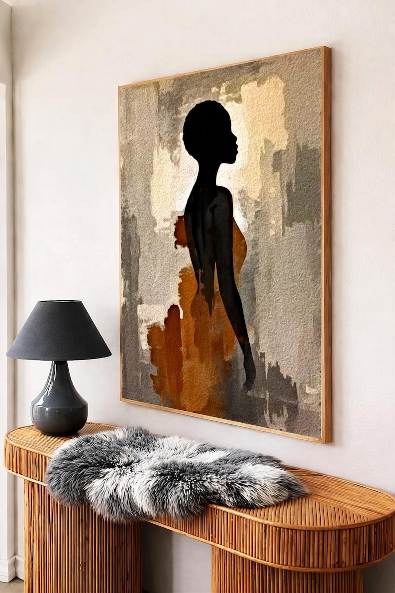K&ouml;nnte beinhalten: Ein rechteckiges Wandbild in einem Holzrahmen mit der schwarzen Silhouette einer Person im Profil vor einem abstrakten Hintergrund aus strukturierten beigen, grauen und rostorangen Pinselstrichen, pr&auml;sentiert an einer Wand &uuml;ber einem Rattankonsolentisch.
