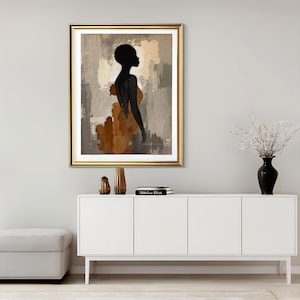 K&ouml;nnte beinhalten: Ein gerahmter Kunstdruck mit der schwarzen Silhouette einer Person vor einem abstrakten Hintergrund aus strukturierten beigen, grauen und braunen Pinselstrichen. Das Kunstwerk befindet sich in einem goldfarbenen Rahmen mit wei&szlig;em Passepartout.