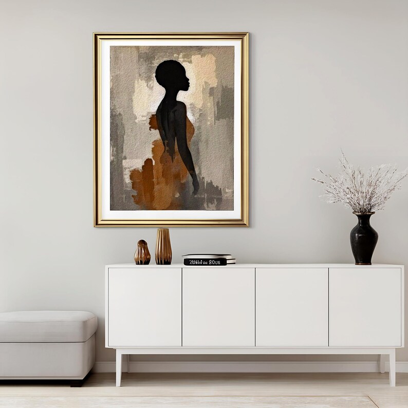 K&ouml;nnte beinhalten: Ein gerahmter Kunstdruck mit der schwarzen Silhouette einer Person vor einem abstrakten Hintergrund aus strukturierten beigen, grauen und braunen Pinselstrichen. Das Kunstwerk befindet sich in einem goldfarbenen Rahmen mit wei&szlig;em Passepartout.