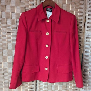 May include: A bright red blazer with a classic design. The jacket features a collared neckline, two front pockets, and gold-colored buttons. The blazer is displayed on a wooden hanger.