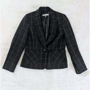 May include: A black blazer featuring a white grid pattern, a single-button closure, notched lapels, and two front patch pockets. The interior label reads Kasper. The garment has long sleeves and a structured fit with a smooth black lining.