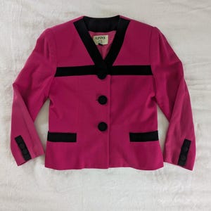 May include: A magenta blazer with black trim and buttons. The blazer has a V-neckline with black lapels, a black horizontal stripe across the chest, and black accents on the cuffs and pockets. The label reads "KASPER 4SL".