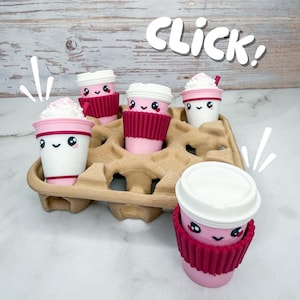 May include: A white ceramic mug with a black handle and the text "But First, Coffee" in a black, handwritten-style font. The mug is on a white surface.