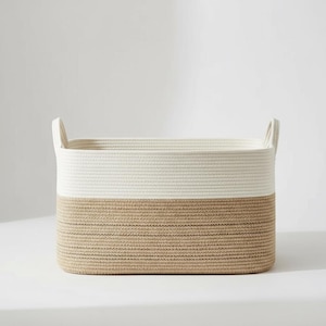 May include: A rectangular storage basket in cream and light brown. The basket has two handles and is made of woven material. The top half is cream, and the bottom half is light brown.
