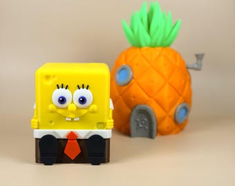 May include: A yellow, square SpongeBob SquarePants figure with blue eyes, a smiling face, and a red tie. Beside it is an orange pineapple house with green leaves and blue windows.