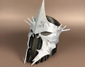 May include: A silver helmet with a central spike and smaller spikes around the crown. The helmet has a textured surface and a dark interior. The design suggests a fantasy or cosplay theme.