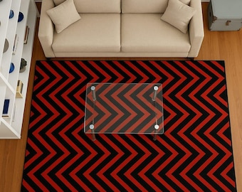 May include: Overhead view of a living room with a beige sofa, two throw pillows, and a glass-top coffee table. A large red and black zigzag patterned rug covers the floor, adding a bold design element to the space.