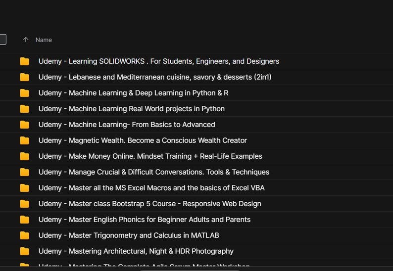 May include: A screenshot of a computer file directory with a black background. The directory lists various Udemy courses, including topics like SOLIDWORKS, Machine Learning, and Web Design. The file names are in white text.