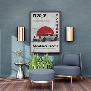 Könnte beinhalten: Gerahmtes Poster mit einem silbernen Mazda RX-7-Auto mit roter Sonnengrafik. Das Poster wird an einer türkisblauen Wand mit zwei goldenen und kupferfarbenen Wandleuchten ausgestellt. Ein blauer Stuhl und ein Hocker mit goldenen Zierleisten stehen vor der Wand.