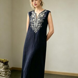 May include: A navy blue sleeveless dress with white floral embroidery. The dress has a V-neck and a relaxed fit. The embroidery is around the neckline and hem. The dress is a midi length, approximately 120 cm long, and is suitable for warm weather.