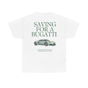 Może przedstawiać: Biała koszulka z zielonym napisem "SAVING FOR A BUGATTI" nad srebrną grafiką samochodu. Poniżej samochodu znajduje się napis "DELAYED GRATIFICATION PERMANENT ELEVATION".