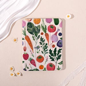 May include: A rectangular tablet case featuring a repeating pattern of colorful vegetables and fruits, including orange carrots, red tomatoes, purple onions, green leafy greens, and red strawberries on a light cream-colored background.