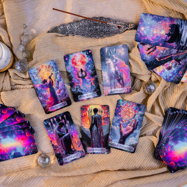 May include: A collection of tarot cards with vibrant, cosmic artwork. The cards feature illustrations of figures, celestial bodies, and symbols. The cards are arranged on a beige cloth, with a decorative incense holder and crystals.