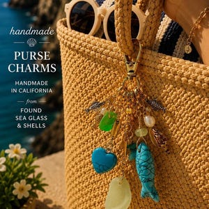 May include: A gold-toned metal lobster clasp keychain featuring various charms including a turquoise heart, a turquoise fish, smooth sea glass pieces in green and pale yellow, a small white pearl, a seashell, and tiny metallic fish-shaped charms.