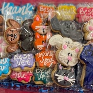 May include: A variety of decorated sugar cookies in a clear plastic bag. The cookies feature paw prints, animal faces, and messages like "Thank You" and "Best Vet".