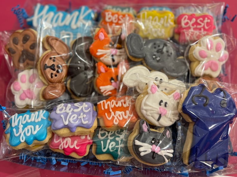 May include: A variety of decorated sugar cookies in a clear plastic bag. The cookies feature paw prints, animal faces, and messages like "Thank You" and "Best Vet".