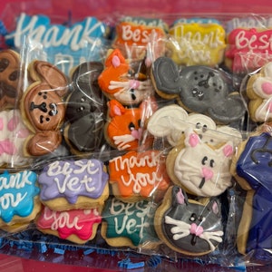 May include: A variety of decorated sugar cookies in a clear plastic bag. The cookies feature animal designs, paw prints, and the text "Thank You" and "Best Vet".
